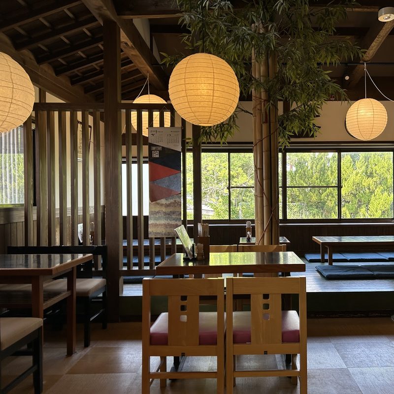 提灯の下に木の椅子と座敷が並ぶ店内