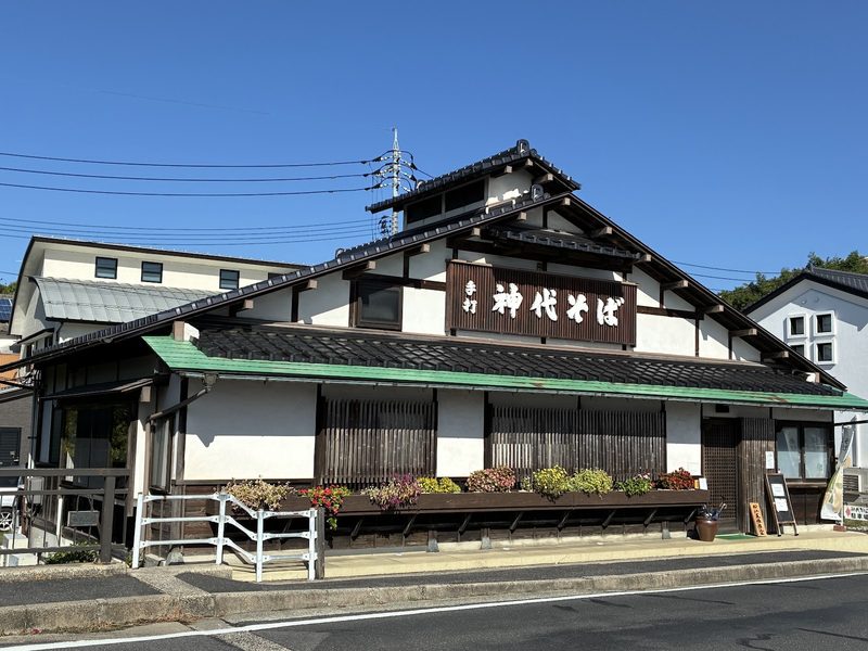 白壁と緑の庇に「神代そば」の看板を掲げた、木造二階建ての店構え